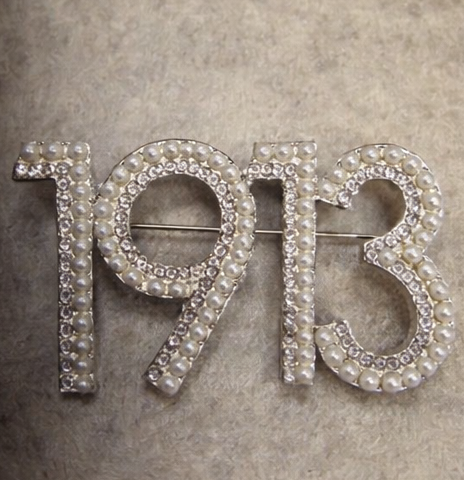 Brooch with '1913' design on a textured gray background